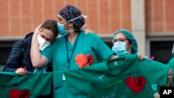 Health workers comfort each other during a memorial for a co-worker who died of COVID-19, at the Severo Ochoa Hospital, in Leganes, Spain, April 10, 2020. 