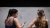 Two women sit on a bench looking at their phone in central Sydney on November 7, 2024.