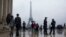 People walk past by French police officers, as they patrol at Trocadero plaza with the Eiffel Tower in the background in Paris, France, Saturday, May 6, 2017.