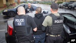 FILE - photo released by U.S. Immigration and Customs Enforcement shows foreign nationals being arrested this week during a targeted enforcement operation conducted by U.S. Immigration and Customs Enforcement (ICE).