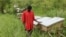 Latib Kalema stands beside the bee hives that have been preventing elephants from crossing to raid his crops, September 28, 2012. (H. Heuler/VOA)