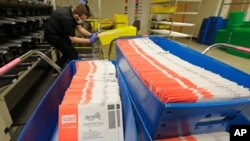 Vote-by-mail ballots are shown in sorting trays, Wednesday, Aug. 5, 2020, at the King County Elections headquarters in Renton, Wash., south of Seattle. Washington state has offered voting by mail since 2011. (AP Photo/Ted S. Warren)