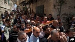 Hrišćanski hodočasnici nose krst prema Crkvi svetog Groba u Jerusalimu. 