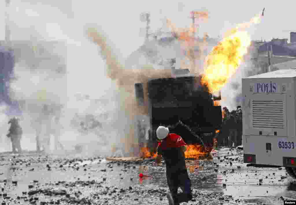 A protester throws a petrol bomb towards a crowd control vehicle in Taksim Square in Istanbul, June 11, 2013. 