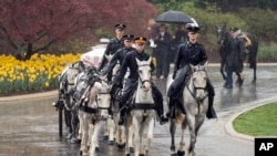 Cubierto con un plástico el ataúd de John Glenn es trasladado en una carroza tirada por caballos hasta el lugar de su sepultura en el Cementerio Nacional de Arlington.