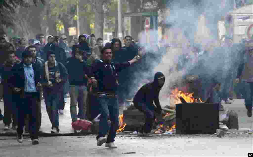 Demonstrators throws stones at police during clashes in Tunis, Friday, Jan. 14, 2011.