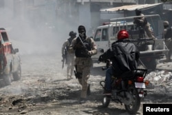 Police officers patrol after dissipating demonstrators after gangs set several houses on fire, in Port-au-Prince, Haiti, Aug.19, 2024.