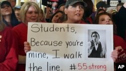 Jennifer Hanner, a first-year teacher from Harts, W.Va., center, holds a sign outside the state Senate chambers at the Capitol in Charleston, W.Va., Feb. 22, 2018.