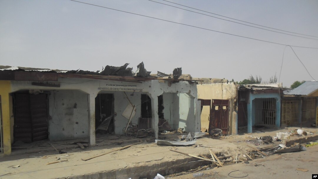 Bloodstains seen on the street and damage buildings following a suicide bomb explosion at a World cup viewing centre in Damaturu, Nigeria, Wednesday, June 18, 2014. Police say 14 people were known to have died in the bombing of an outdoor World Cup viewin