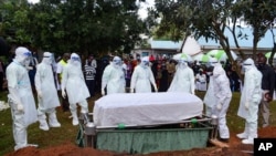 Health officials wearing personal protection equipment prepare to bury coronavirus victim Dr. Doreen Adisa Lugaliki at her burial in Ndalu, Bungoma county, Kenya Monday, July 13, 2020. Lugaliki, a consultant obstetrician and gynecologist and mother…