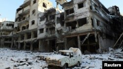 Sebuah mobil yang rusak dan bangunan yang tertutup salju terlihat di daerah Jouret al Shayah, Homs, Suriah, 10 Januari 2013. (Foto: dok). Para aktivis melaporkan pasukan yang setia kepada Presiden Assad telah menewaskan lebih dari 100 orang di Homs, Suriah Tengah.