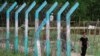 A Rohingya refugee girl walks past a camp border fence at a refugee camp, in Cox's Bazar