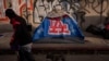 FILE - A man walks past a homeless encampment in downtown Los Angeles, Oct. 25, 2023. 