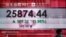 A man wearing a face mask walks past a bank's electronic board showing the Hong Kong share index at Hong Kong Stock Exchange, July 6, 2020.