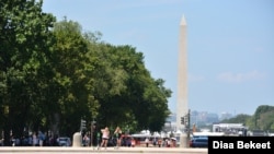 Para turis berkumpul dekat kolam Capitol dengan latar Monumen Washington saat cuaca panas di Washington D.C. deng suhu udara mencapai titip atas 80 Fahrenheit, Jumat, 19 Juli 2019. (Foto: Diaa Bekheet)