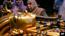 Wasu mata su na kallon mutum-mutumin gwal da aka rufe akwatin gawar wani fir'auna mai suna Tutankhamun, wanda yayi mulki tun yana dan karamin yaro, ya kuma mutu yana dan yaron.