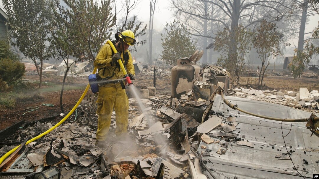 A firefighter with the Montezuma Fire District puts out hot spots at a home destroyed by fire Sunday, Sept. 13, 2015, in Middletown, California.