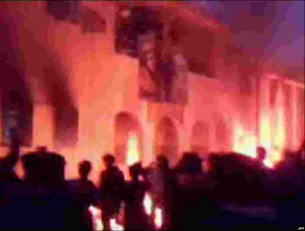 In this footage taken from amateur video, people watch papers falling from a window as a police station burns, in Tobruk, Libya, Monday Feb. 21, 2011. Libya has seen the bloodiest crackdown of any Arab country of the wave of protests sweeping the region t