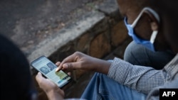 A man looks at his smartphone in Kigali, Rwanda, May 18, 2020, showing an article about the arrest of Felicien Kabuga, a fugitive wanted over the 1994 Rwandan genocide, who was arrested by French police May 16, 2020, in a Paris suburb. 