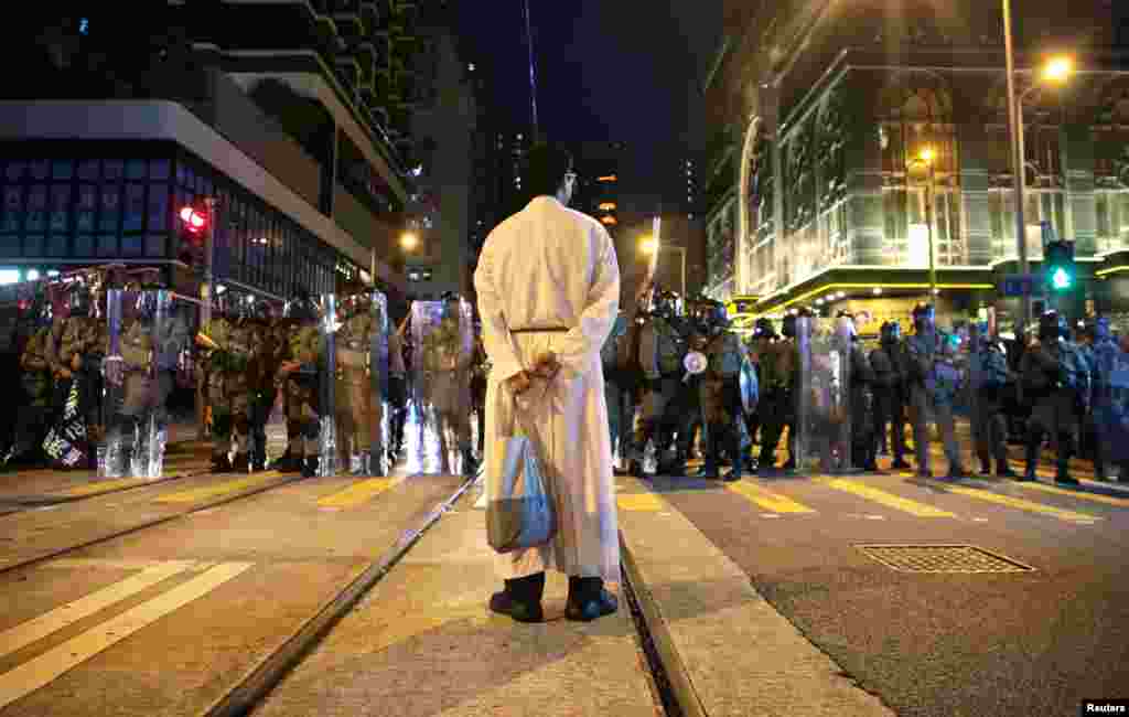 A priest is seen in front of riot police during an anti-extradition bill protest in Kennedy Town, Hong Kong.