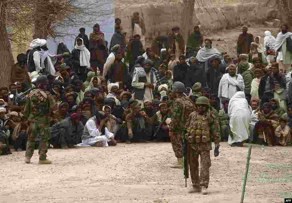 Afghan National Army soldiers keep watch as Afghans gather outside a U.S. base in Panjwai district. (Reuters)