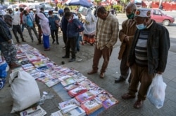 Ethiopians check newspapers and magazines reporting on the current military confrontation in Ethiopia's Tigray region, at a news stand on a street in the capital Addis Ababa, Nov. 7, 2020.