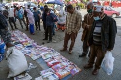 Ethiopians check newspapers and magazines reporting on the current military confrontation in Ethiopia's Tigray region, at a news stand on a street in the capital Addis Ababa, Nov. 7, 2020.