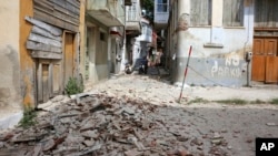 People look at the debris of a damaged building after an earthquake in the village of Plomari on the northeastern Greek island of Lesbos, June 12, 2017.
