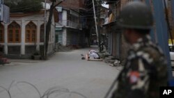 An Indian paramilitary soldier stands guard as Kashmiri Muslims offer Friday prayers on a street outside a local mosque during curfew like restrictions in Srinagar, India, Aug. 16, 2019. 