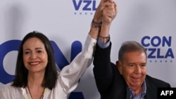 La líder de la oposición venezolana María Corina Machado levanta su mano junto a la del candidato presidencial Edmundo González Urrutia, en Caracas, el 29 de julio de 2024.