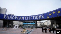 Para pejalan kaki berjalan di bawah poster iklan pemilihan umum Eropa yang dipasang di luar gedung Parlemen Eropa di Brussels, Belgia, 24 Januari 2024. (Foto: Virginia Mayo/AP Phot)