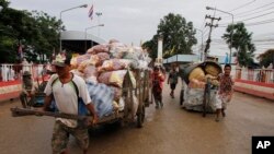 FILE PHOTO - Cambodian workers transport their goods brought from Thailand at a Cambodia-Thai international border gate in Poipet, Cambodia, Wednesday, June 18, 2014, for their daily business near the border between Cambodia and Thailand. (AP Photo/Heng S