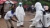 Health workers wash their hands after taking a blood specimen from a child to test for the Ebola virus in an area where a 17-year- old boy died from the virus on the outskirts of Monrovia, Liberia, June 30, 2015.