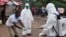 Health workers wash their hands after taking a blood specimen from a child to test for the Ebola virus in an area where a 17-year- old boy died from the virus on the outskirts of Monrovia, Liberia, June 30, 2015.