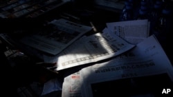A woman arranges Chinese newspapers, as one of them with the headlines of President Donald Trump tested positive for the coronavirus, at her newsstand in Beijing, Saturday, Oct. 3, 2020. President Trump said Friday that he and first lady Melania…