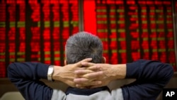 FILE - A Chinese investor watches stock prices at a brokerage house in Beijing, Sept. 16, 2015.