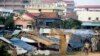 FILE - A young Cambodian woman rides a bicycle near slum homes, Feb. 19, 2009, on the outskirts of Phnom Penh, Cambodia. 