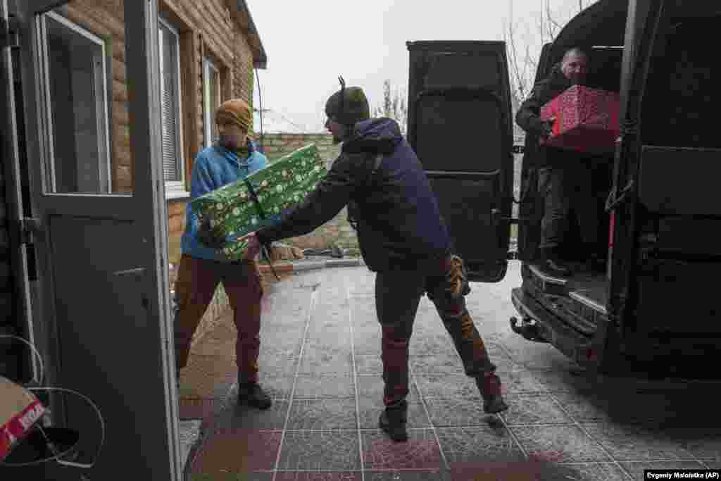 Voluntarios de la ONG local Ukrainian Frontiers descargan regalos de una camioneta antes de las celebraciones del Día de San Nicolás en Izium, Ucrania, el 6 de diciembre de 2024