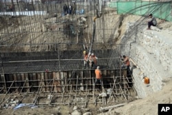 Afghan laborers work on a bridge project funded by the government, in Kabul, Afghanistan. Rebuilding war-torn Afghanistan has cost thousands of lives, according to a new U.S. government report.