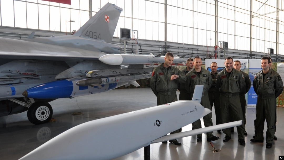 A group of Polish Air Force pilots stand next to a F-16 fighter jet and a model of a JASSM missile as they attend a contract signing ceremony of 40 Lockheed Martin’s joint air-to-surface standoff missiles (JASSM), as well as F-16 fighter plane…