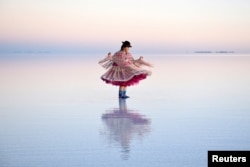 A woman in a Cholita dress poses for photos, at the Uyuni Salt Flat in Bolivia March 26, 2022. (REUTERS/Claudia Morales)