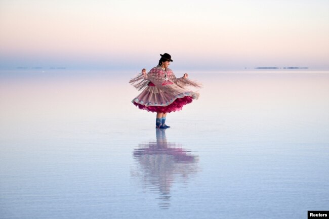 A woman in a Cholita dress poses for photos, at the Uyuni Salt Flat in Bolivia March 26, 2022. (REUTERS/Claudia Morales)