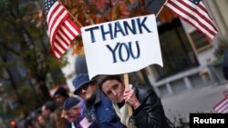 Una mujer muestra un cartel de agradecimiento durante un desfile en Nueva York por el Día de los Veteranos.