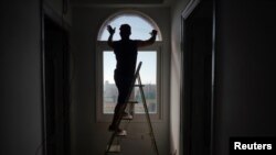 A man applies tape to a window securing it ahead of the anticipated arrival of Tropical Storm Elsa, in Havana, Cuba, July 4, 2021. 