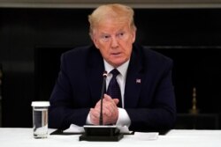 President Donald Trump listens during a meeting with restaurant industry executives about the coronavirus response, in the State Dining Room of the White House, May 18, 2020, in Washington.