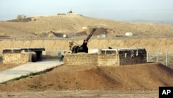 A security man stands next to an anti-aircraft gun as he looks around Iran's nuclear enrichment facility in Natanz, 300 km south of capital Tehran, in this 2007 file photo.