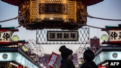 Para pengunjung mengenakan masker di kuil Sensoji, distrik Asakusa, Tokyo, di tengah pandemi Covid-19, 17 Desember 2020. (Foto: Philip FONG / AFP)