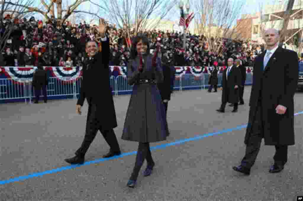 Presiden Barack Obama dan ibu negara Michelle Obama melambaikan tangannya saat berjalan di Pennsylvania Avenue, Washington, dalam parade inaugurasi.