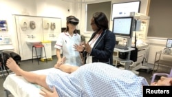 Midwifery educator at Middlesex University Sarah Chitongo instructs a trainee midwife wearing an augmented reality (AR) headset in London, Britain, June 17, 2019.