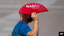 스페인 마드리드시에서 한 남성이 부채로 해를 가리고 있다. 